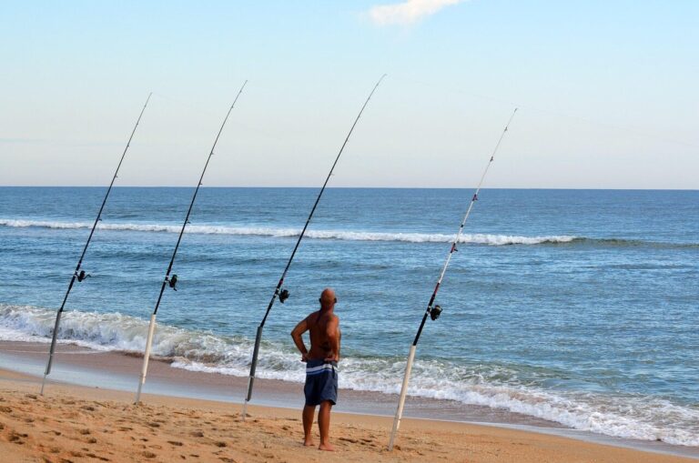 Outer Banks surf fisherman with multiple rods in sand spikes along the shoreline, casting into the breaking surf.