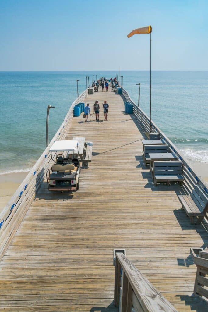 Visitors walking along Avalon Pier in Kill Devil Hills, enjoying a sunny day.
