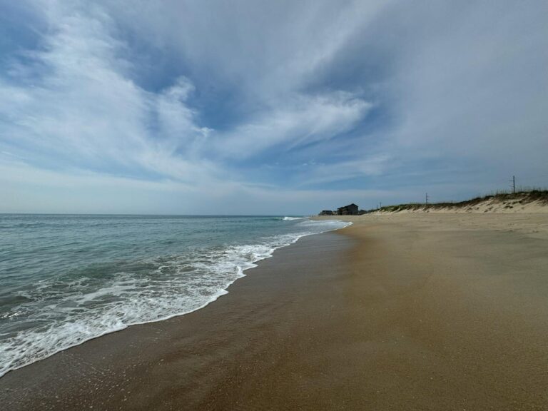Capture the tranquility of Hatteras, NC, with a serene beach under clear skies.