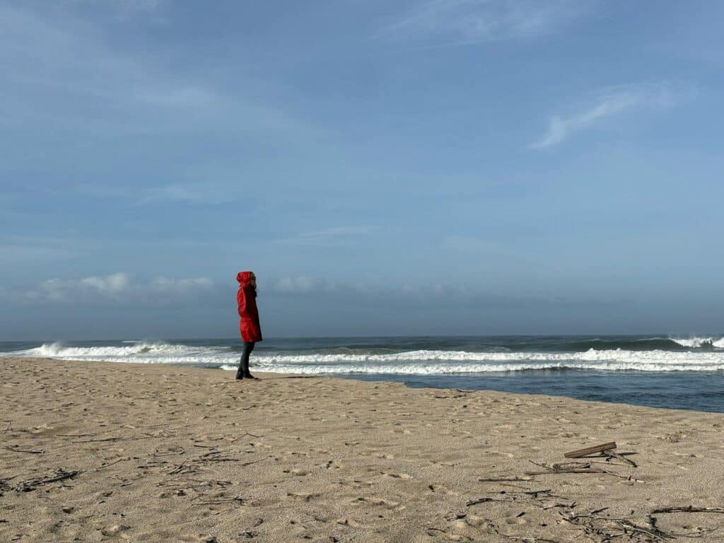A lone angler in a red coat walks the empty winter beach on the Outer Banks