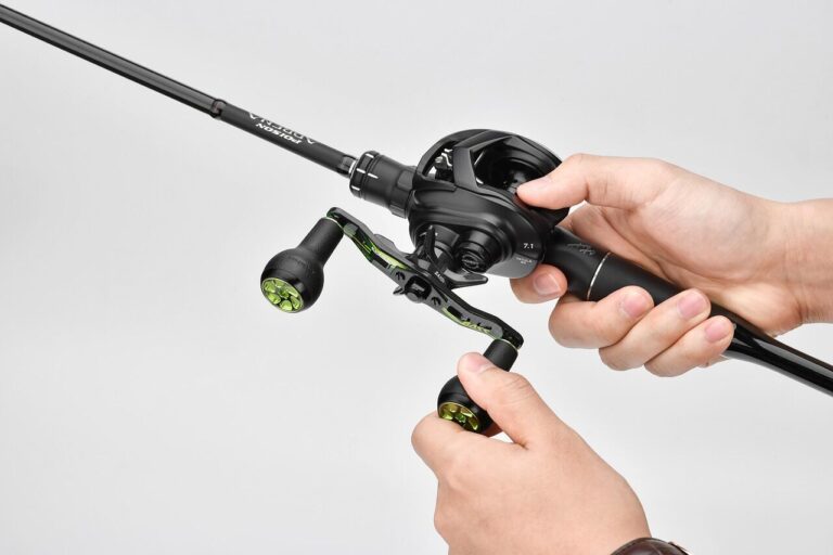 Close-up of a baitcasting reel mounted on a surf fishing rod, showing the carbon handle and TPE knob ready for casting.