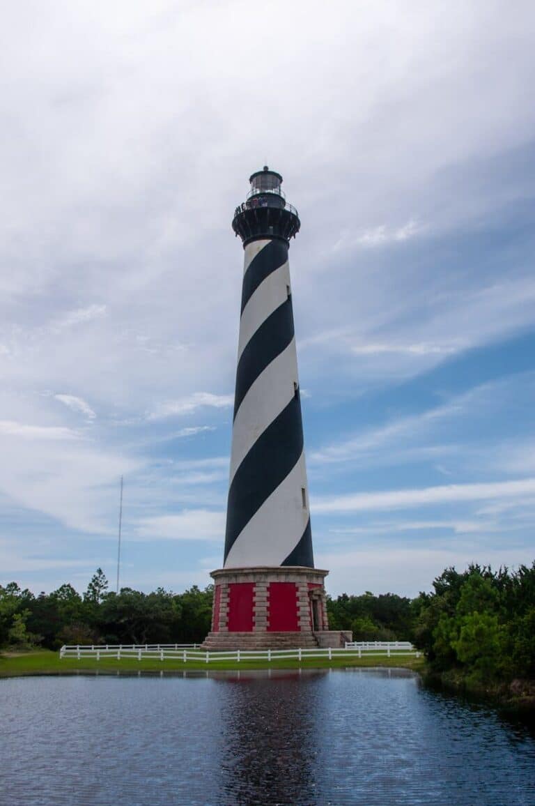 Iconic black and white striped lighthouse at Cape Hatteras on a sunny day with clear blue skies.