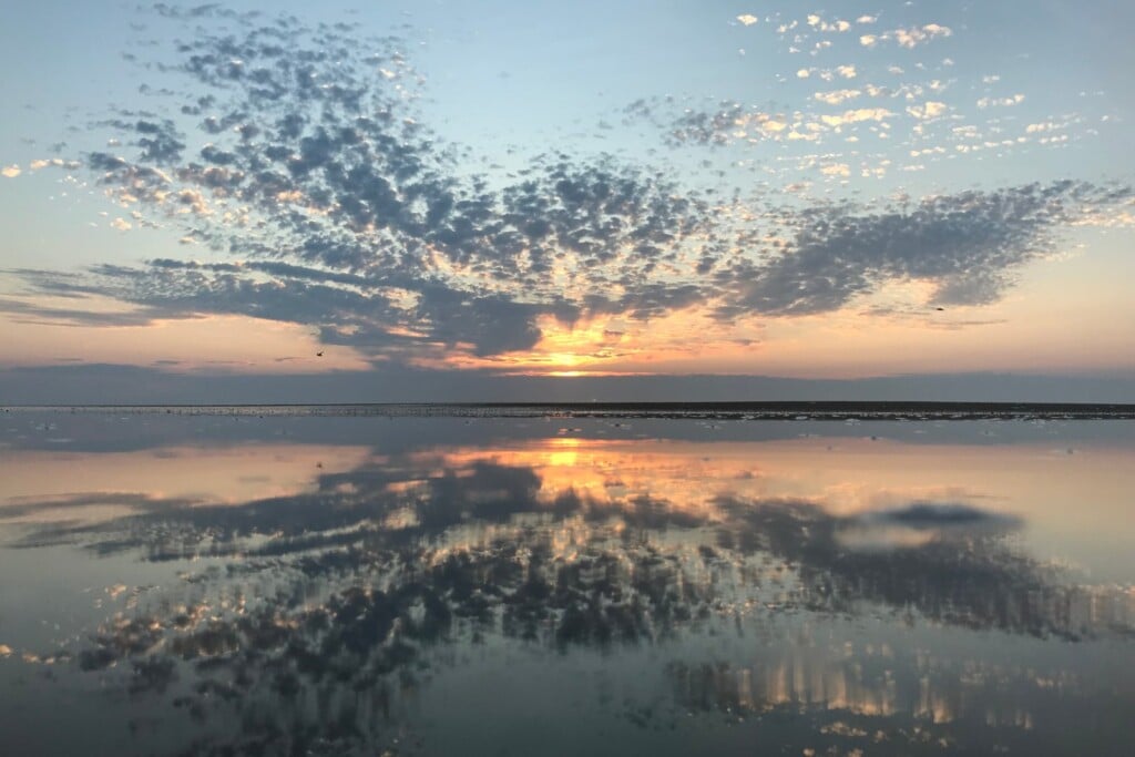 Sunrise reflected in calm sound-side shallows with a mackerel sky over Ocracoke Island