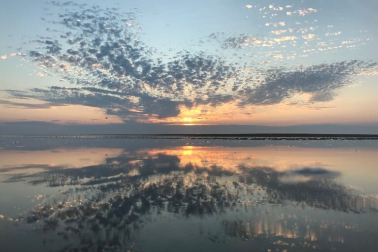Sunrise reflected in calm sound-side shallows with a mackerel sky over Ocracoke Island