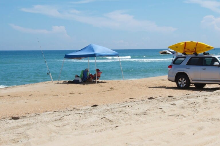 A beach vehicle, shade canopy and surf rods set up at the water’s edge in Cape Hatteras National Seashore