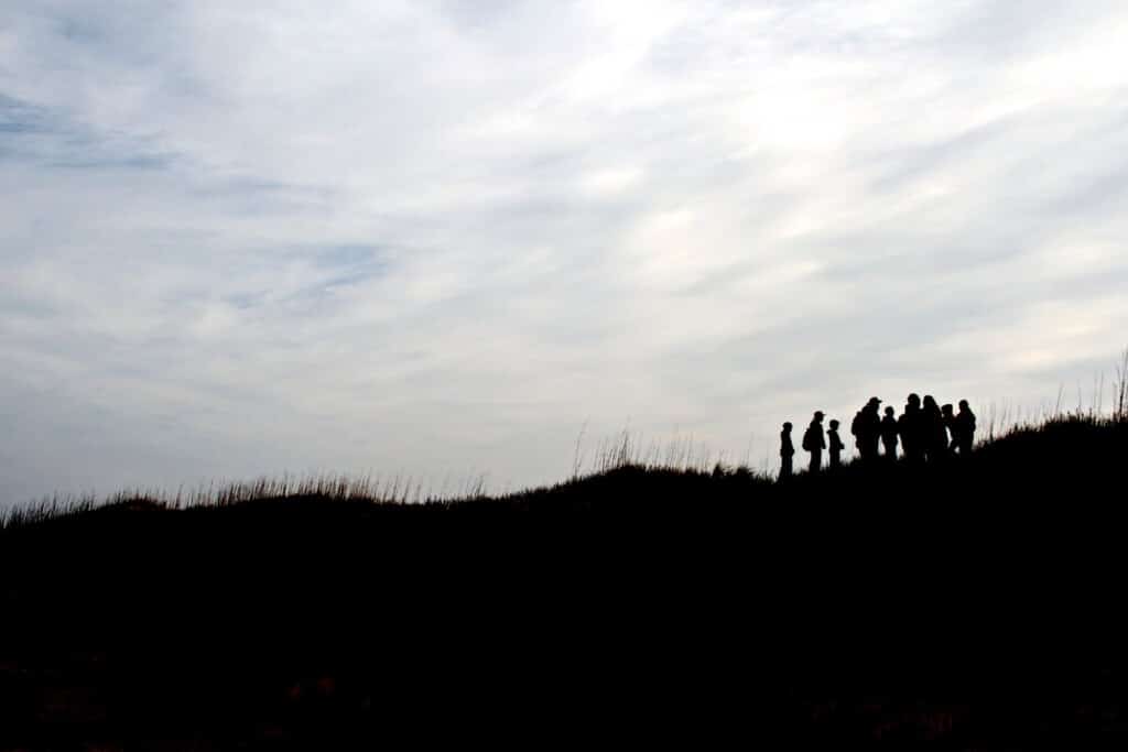 People silhouetted on top of a dune against a cloudy sky at Cape Hatteras National Seashore