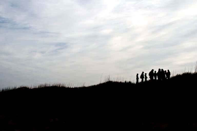 People silhouetted on top of a dune against a cloudy sky at Cape Hatteras National Seashore