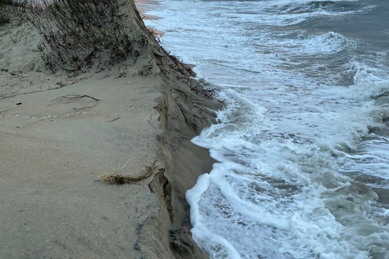Surf breaking against a steep eroded dune scarp at the end of the bypass road south of Ramp 44 near Cape Point