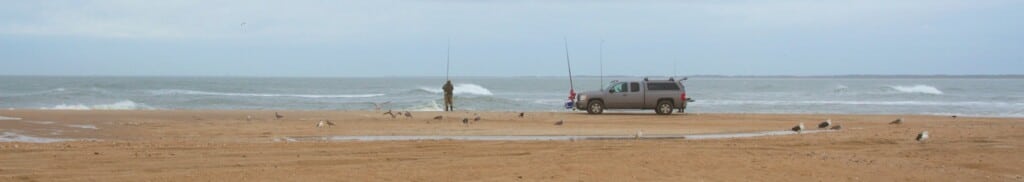 Wide panoramic view of anglers surf fishing along the beach at Cape Point, Hatteras Island