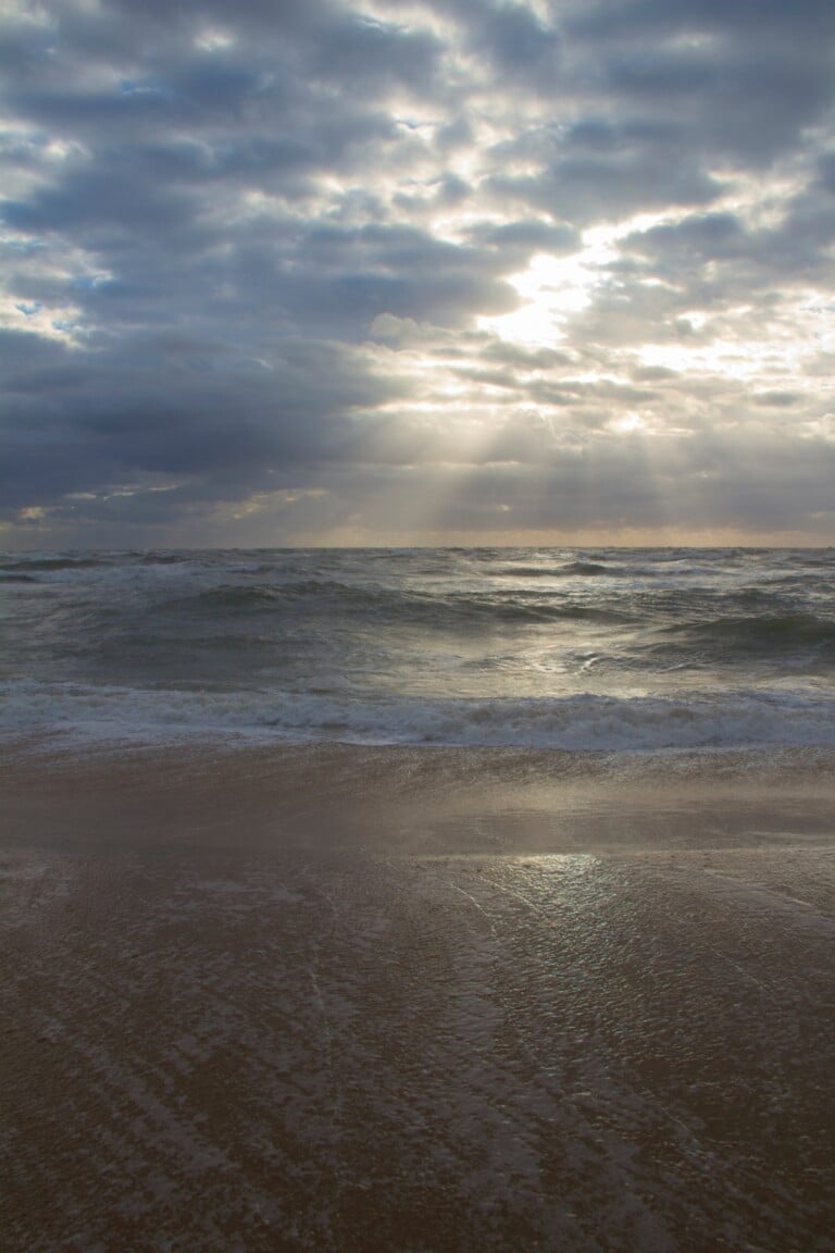 Sunlight breaking through clouds over the Atlantic Ocean surf on the Outer Banks at sunrise