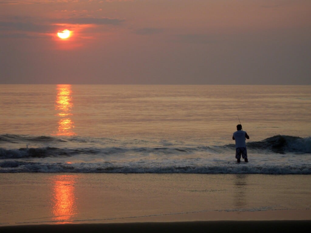 Lone surf fisherman casting into the ocean at sunrise on Cape Hatteras National Seashore