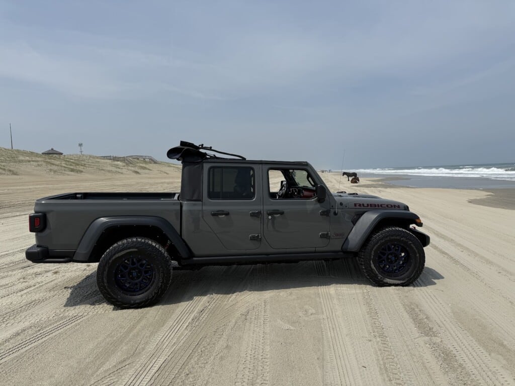 A Jeep Gladiator Rubicon on the sand with an empty bed, Outer Banks