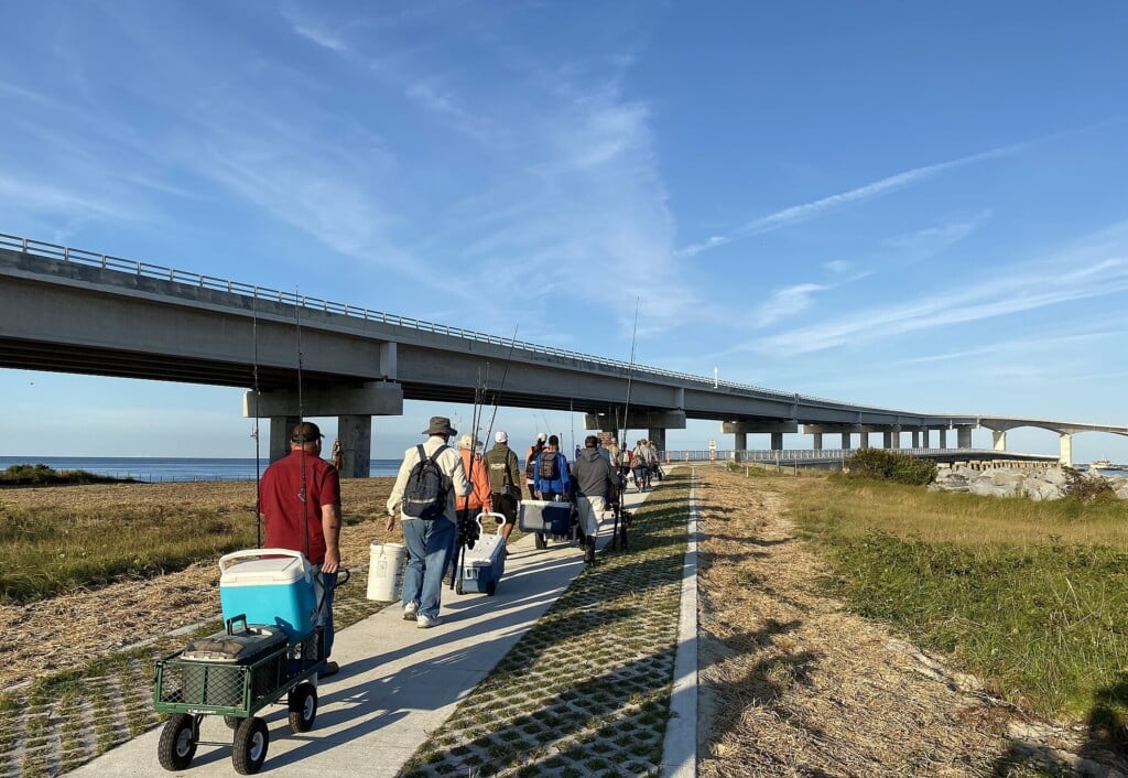 Anglers with carts and rods walking out to the Bonner Bridge Pier under the new Oregon Inlet bridge
