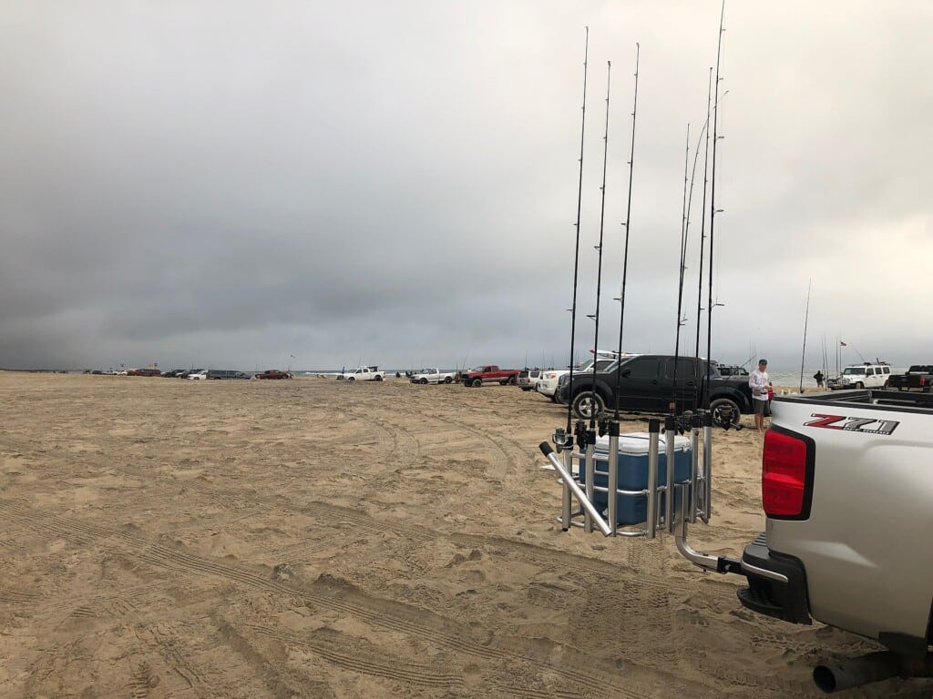 Anglers at Cape Point in October with surf rods racked on the front of a truck