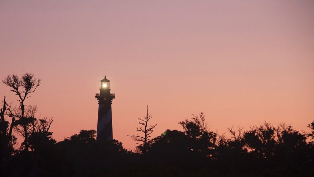 Pink dawn sky over Cape Hatteras with the lighthouse beam still lit