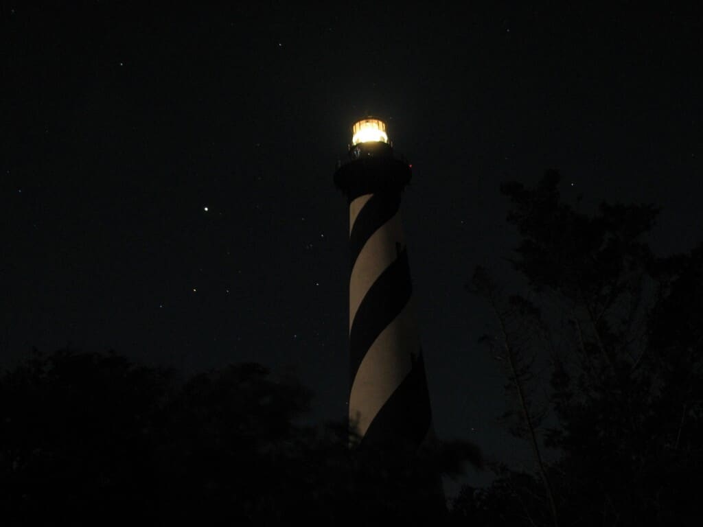 Cape Hatteras Lighthouse lit at night under a starry sky