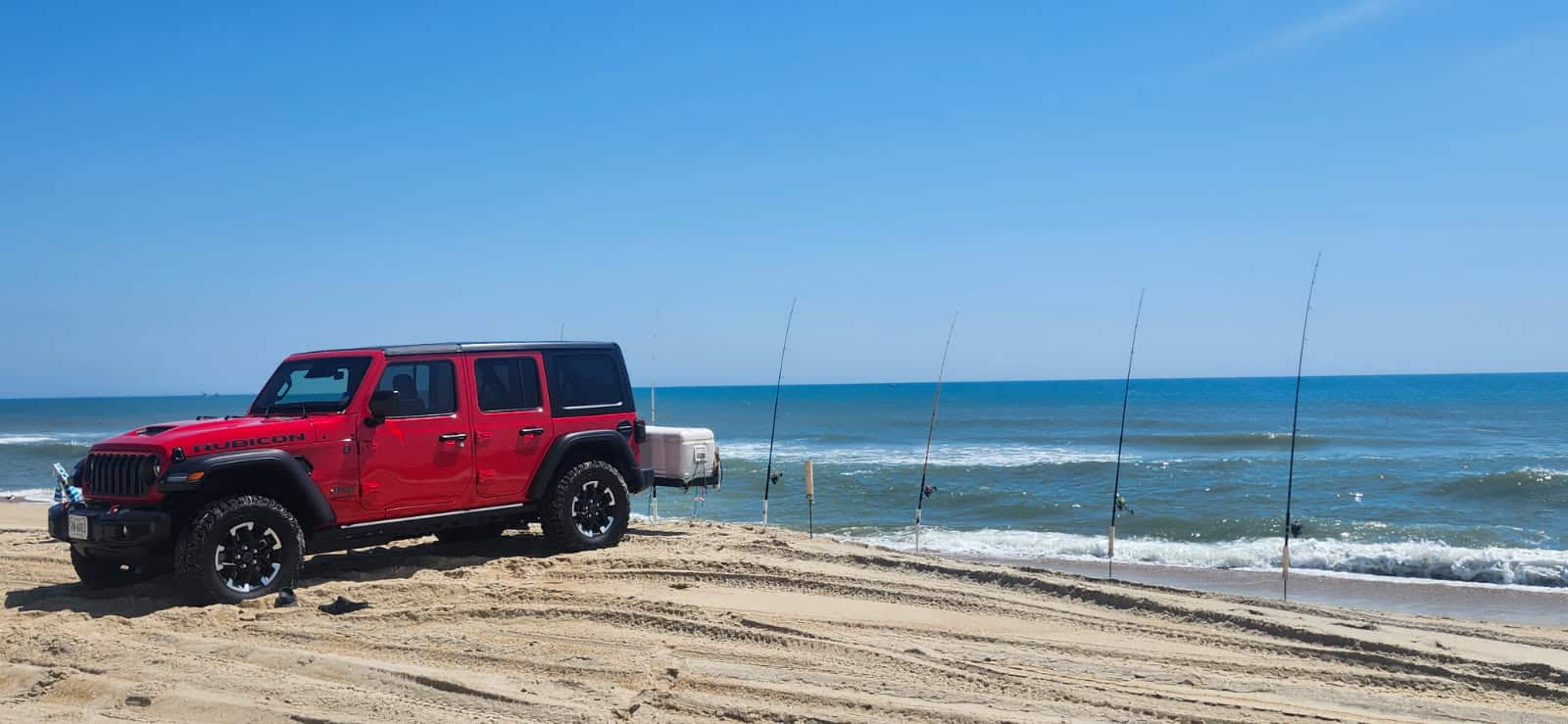 A Jeep Wrangler and surf fishing cart parked on an Outer Banks beach