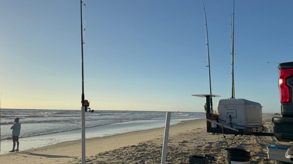 Surf rods and a cooler riding on a hitch-mounted rack behind a pickup at sunrise on an Outer Banks beach
